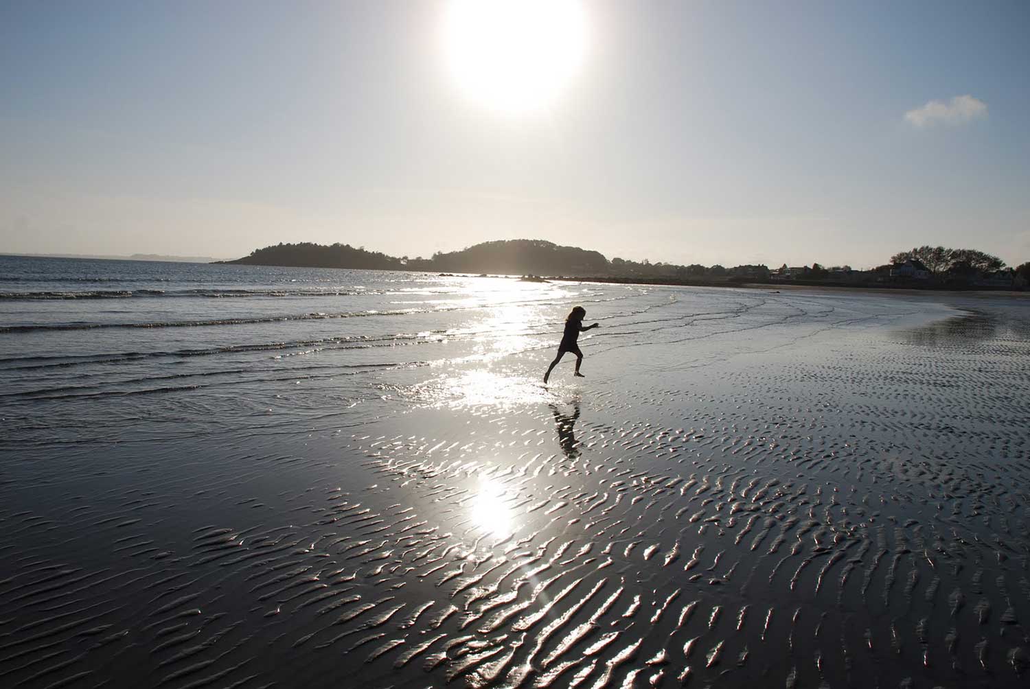 A girl running along a Nahant beach in summer